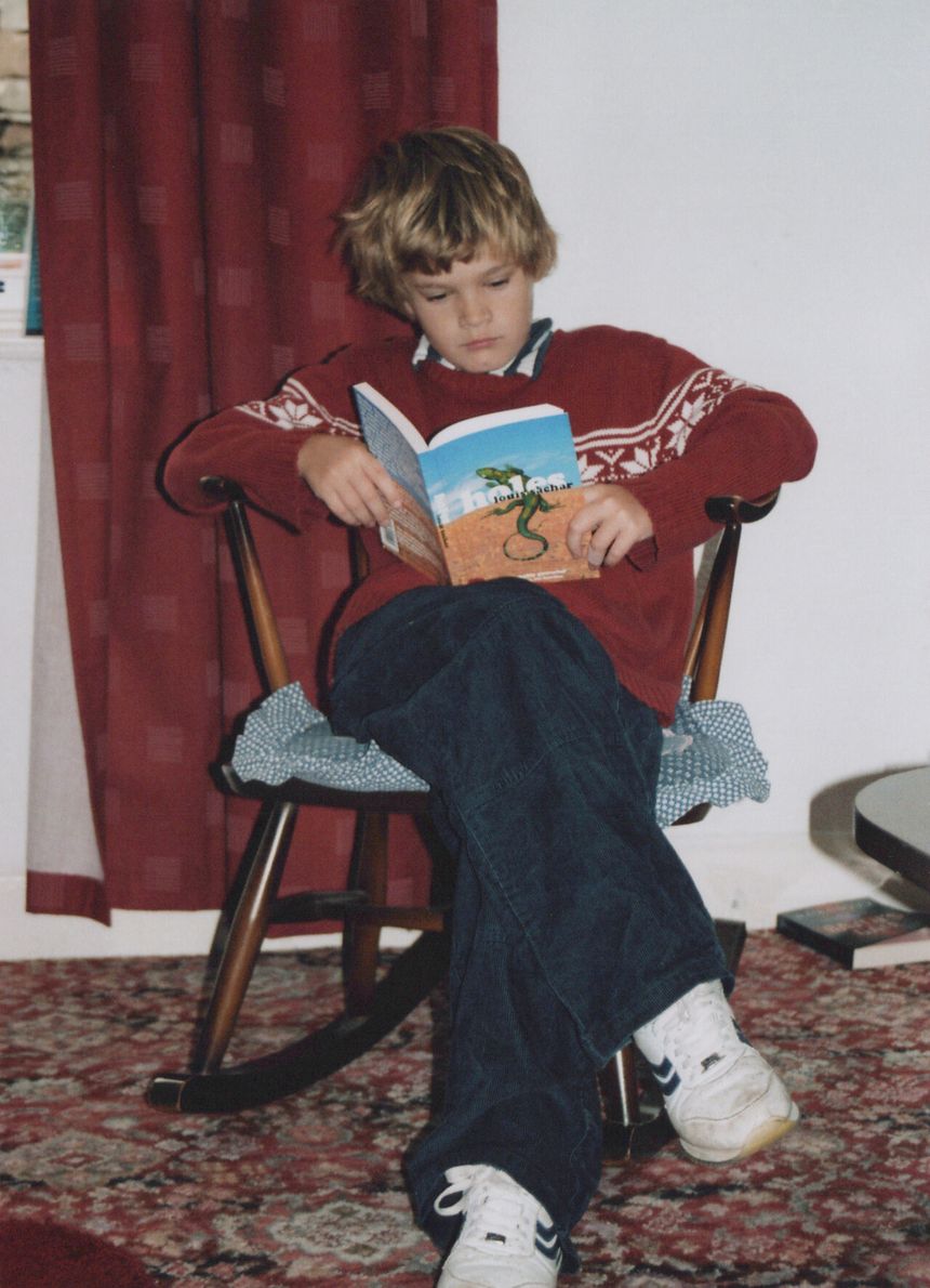 Young Guy in a rocking chair, reading Holes by Louis Sachar
